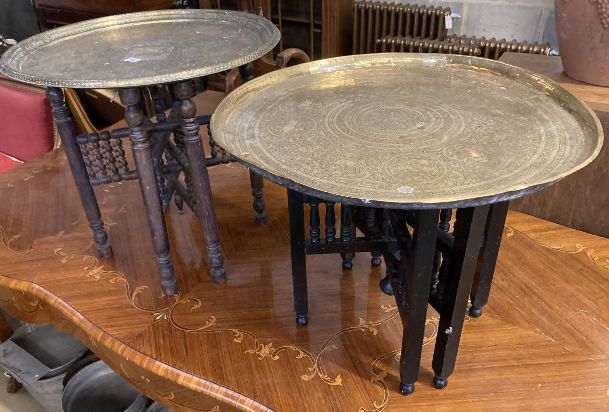 Two Benares engraved circular tray top tables, larger 59cm diameter, 53cm high